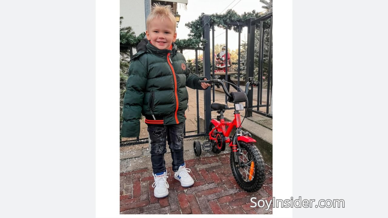 Niño feliz posando junto a su bicicleta con pedales ideal para niños pequeños, segura y colorida.