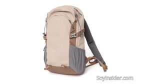 Una mochila de senderismo pequeña y de mujer compacta de color beige con detalles en marrón claro. La mochila cuenta con múltiples bolsillos con cierres de cremallera, bolsillos laterales de malla y correas ajustables con hebillas de plástico. Tiene un diseño ergonómico, con correas acolchadas y un panel trasero de malla para mayor comodidad. En la parte inferior derecha de la imagen aparece la marca "SoyInsider.com".