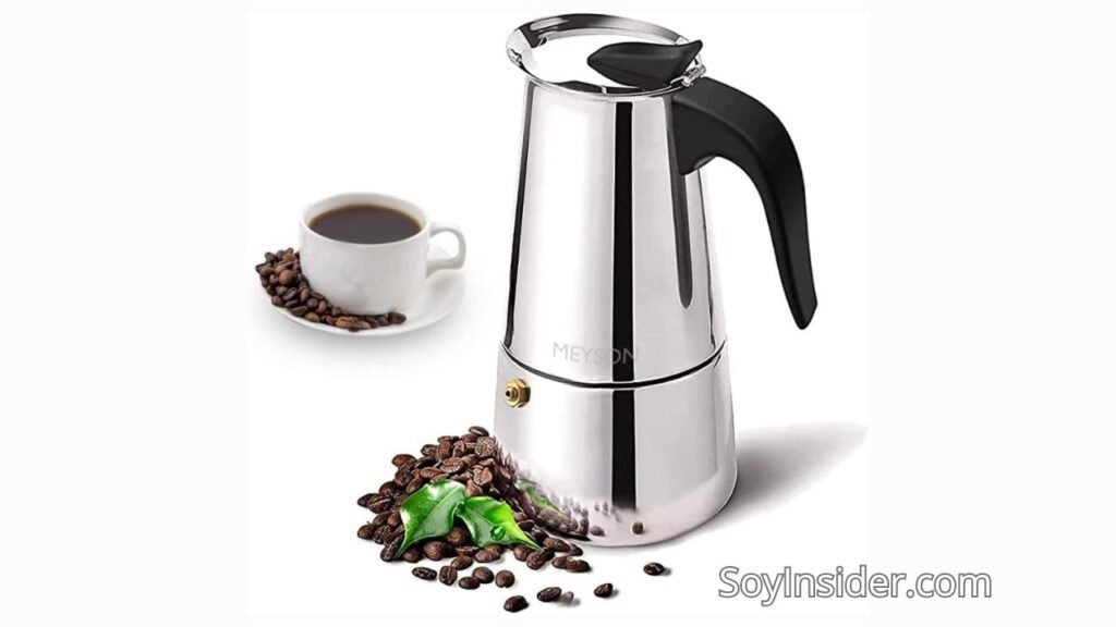Cafetera italiana MEYSON de acero inoxidable, ideal para preparar café espresso en casa. La imagen incluye una taza de café servida rodeada de granos de café, además de una pila de granos con una hoja verde fresca, resaltando la frescura y calidad del café. En la esquina inferior derecha el nombre del sitio web "soyinsider.com"