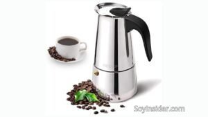 Cafetera italiana MEYSON de acero inoxidable, ideal para preparar café espresso en casa. La imagen incluye una taza de café servida rodeada de granos de café, además de una pila de granos con una hoja verde fresca, resaltando la frescura y calidad del café. En la esquina inferior derecha el nombre del sitio web "soyinsider.com"