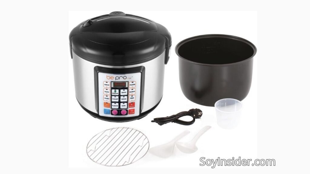 Imagen de una olla robot de cocina programable de la marca "be pro". La olla tiene un diseño en acero inoxidable y negro, con un panel de control frontal que incluye múltiples botones. En el recuadro del panel se lee: "ARROZ, PASTA, GUSO, POSTRE, LENTO, HORNO, FREIR, YOGURT, VAPOR, PLANCHA, SOPA, CANCELAR". Además, se muestran los accesorios incluidos: una rejilla metálica, un recipiente medidor, dos cucharones y el cable de alimentación. Texto visible en la imagen: "SoyInsider.com".