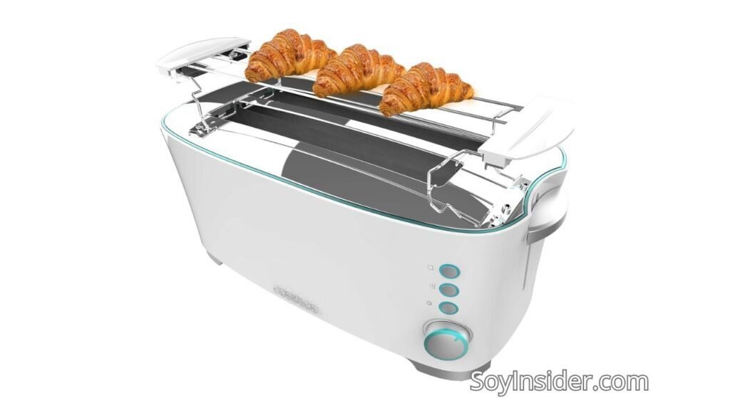 Imagen de una tostadora de pan barata, blanca moderna con diseño minimalista. La tostadora incluye un soporte superior para calentar croissants o panecillos, en el que se observan tres croissants colocados. En el panel lateral, se aprecian tres botones iluminados en color azul y una perilla de control giratoria. Texto visible en la imagen: "SoyInsider.com".