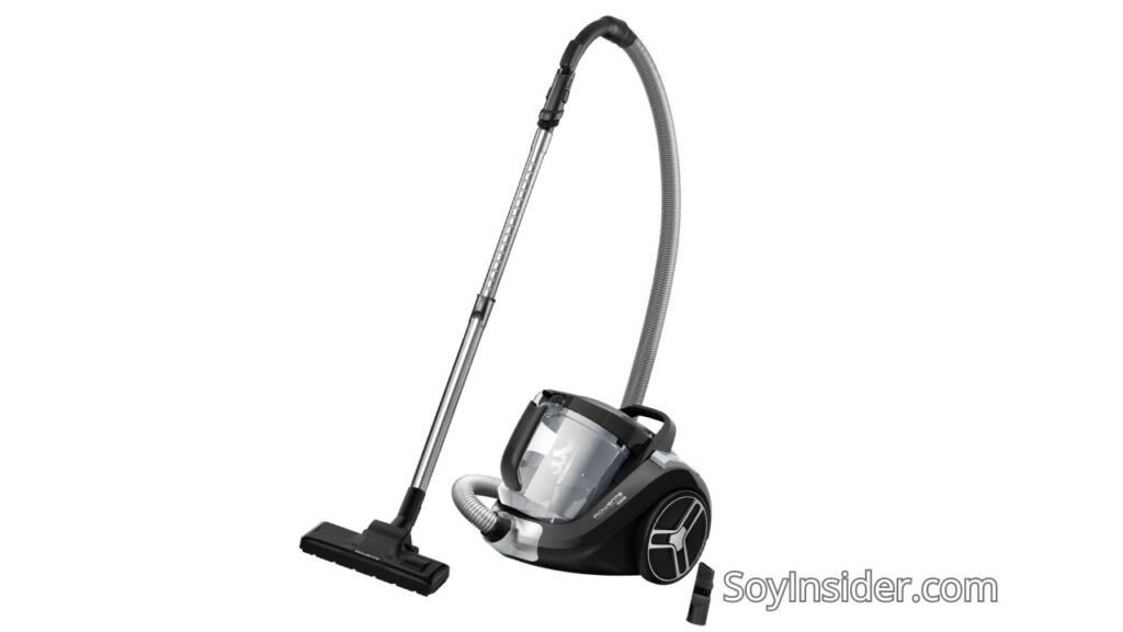 Imagen de una aspiradora sin bolsa Rowenta Cyclonic Power XXL RO4825. La aspiradora tiene un diseño moderno en color negro con detalles plateados, un tubo metálico telescópico y una manguera flexible gris. Incluye un cepillo principal y un accesorio adicional para limpieza de rincones. Texto visible en la imagen: "SoyInsider.com".