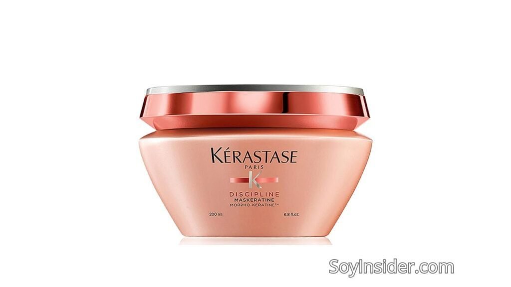 Imagen de un envase de 200 ml de mascarilla capilar de la marca Kérastase, de la línea Discipline. El envase tiene un diseño elegante, con un tono rosado en la base y una tapa metálica de color plateado. El producto está indicado para alisar el cabello y controlar el encrespamiento. Texto visible en la imagen: "SoyInsider.com".