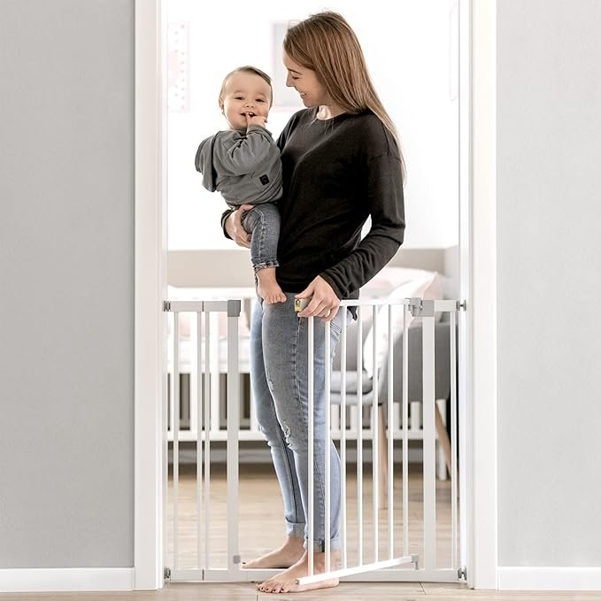 Imagen de la Hauck Barrera de Seguridad para Niños Open N Stop Safety en color blanco, instalada en una puerta, incluye extensión de 9 cm; ideal para proteger escaleras y accesos, ofreciendo máxima seguridad en el hogar.