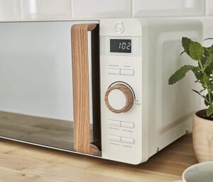 Imagen del horno microondas digital Swan estilo nórdico de 20 litros, color crema, con diseño retro, perillas y pantalla digital, ideal para cocina moderna; posee 6 niveles de potencia y 800 W de potencia para calentar, descongelar y cocinar alimentos.